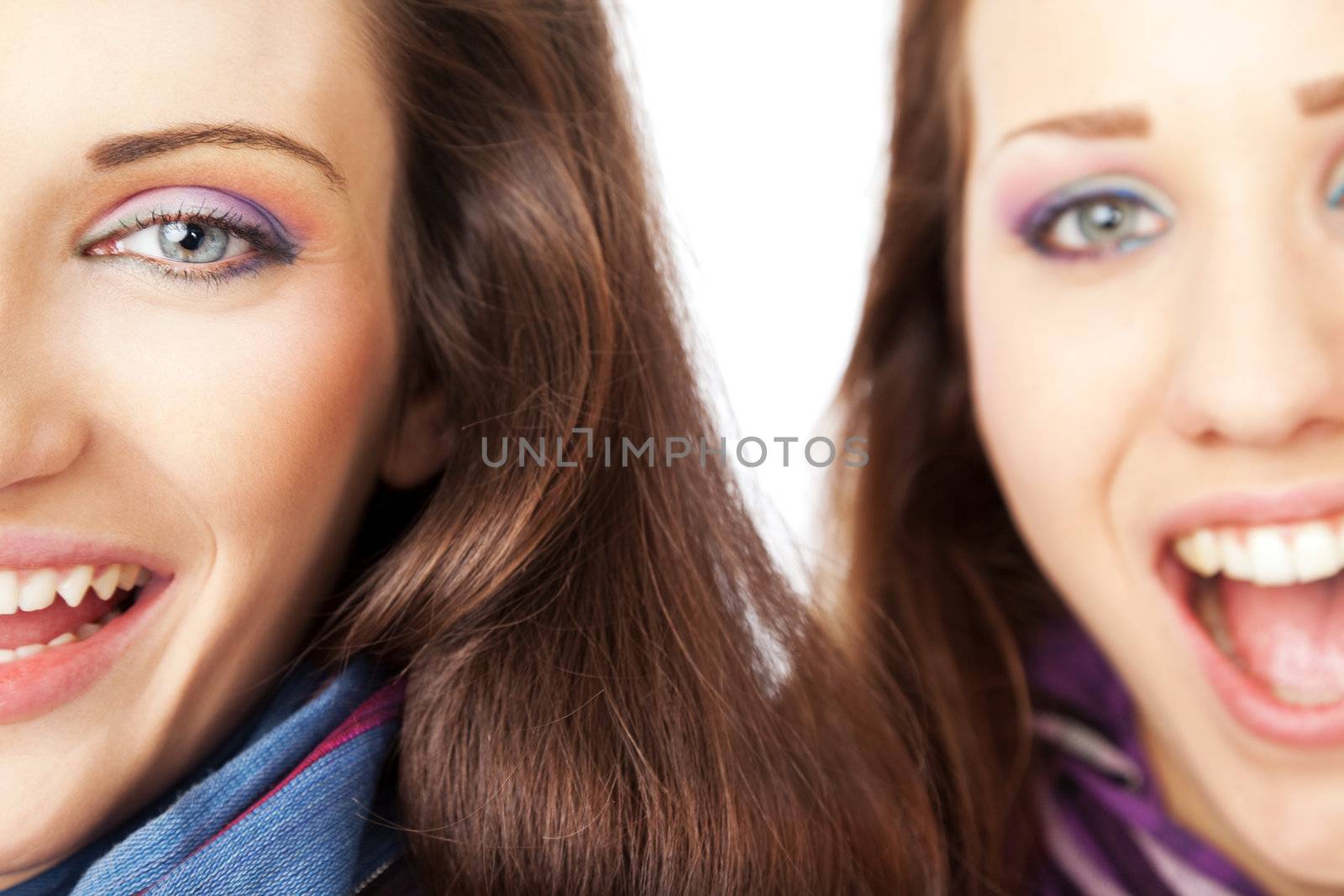 Close-up of two beautiful female half faces, laughing and looking at the camera