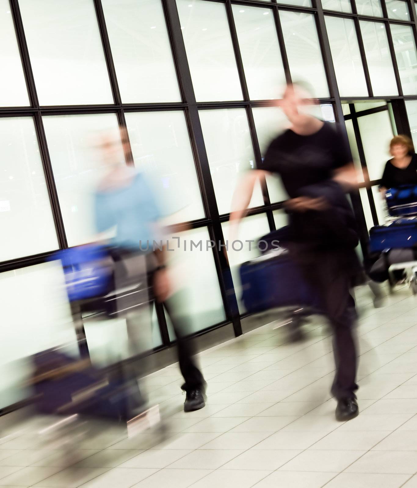 Blurred figures of people with luggage arriving at airport