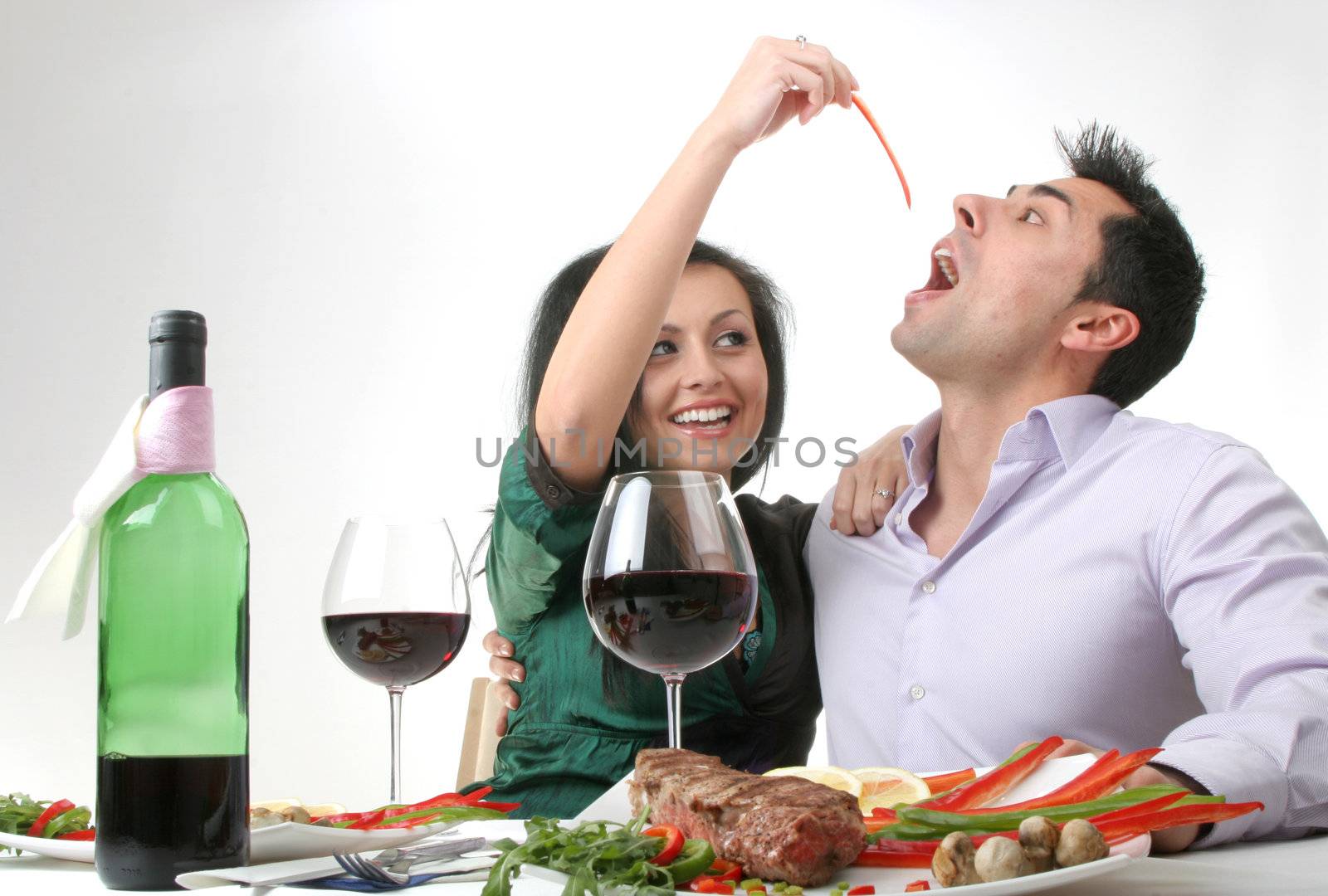 Couple having a romantic dinner with a grilled steak and a bottle of red wine