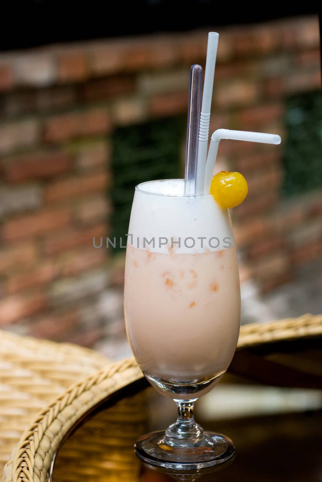 A glass of cocktail drink with straws and fruit