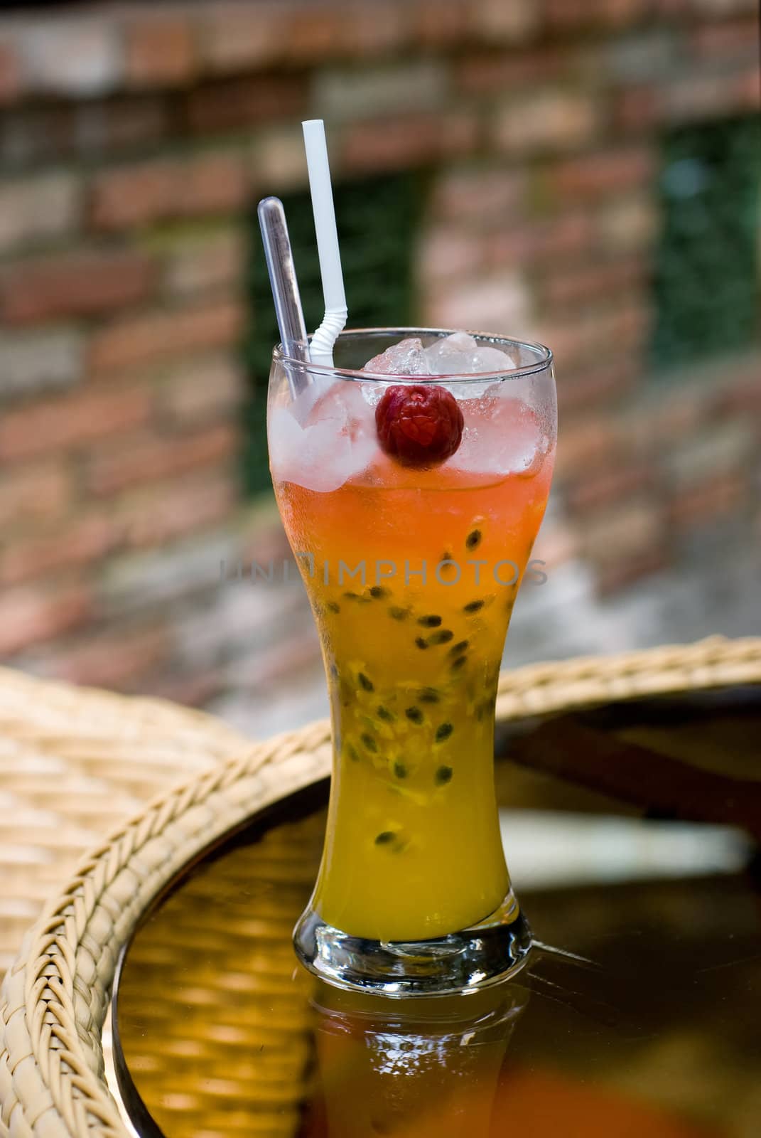 A glass of cocktail drink with straws and fruit