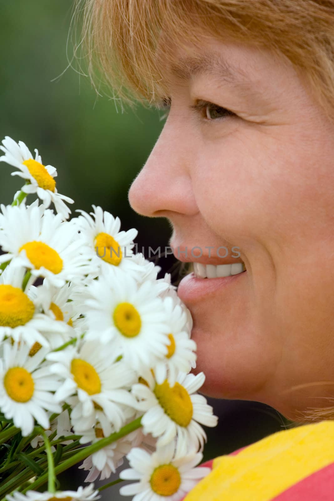 The smiling woman with a bouquet of camomiles