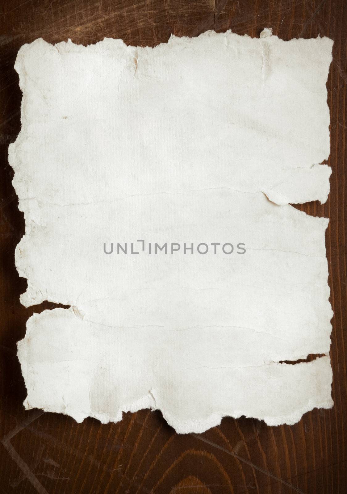 old paper with burnt torn edges on wooden wall, focus point on center