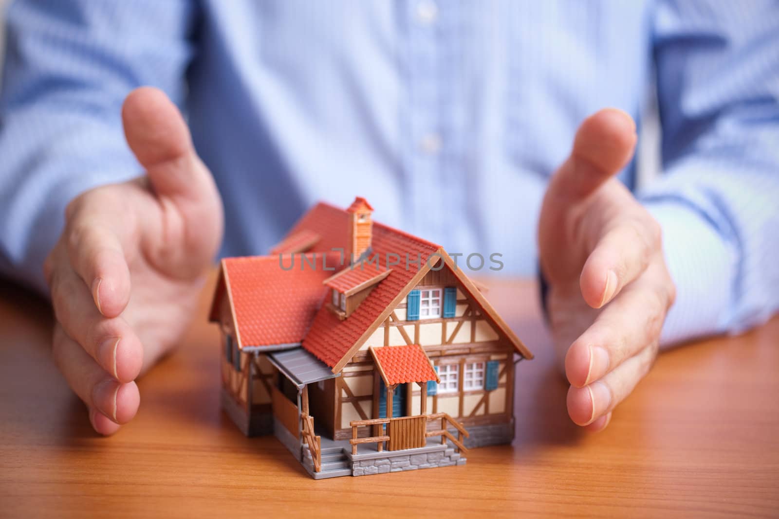 concept with model of house and hands of man, selective focus on nearest part of small building