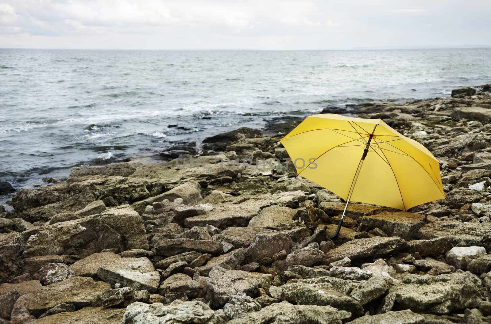 concept,cold sea and gray stones focus point on yellow umbrella