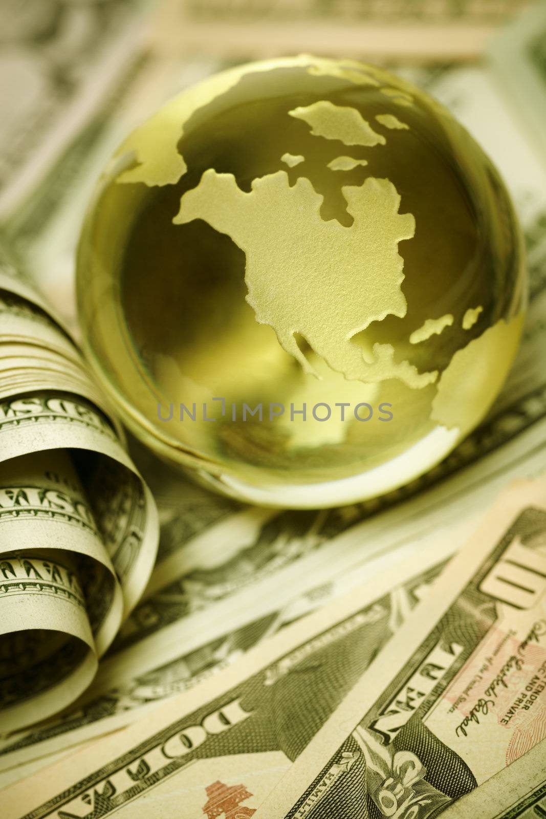 glass globe and US dollar bills in closeup, selective focus on nearest part