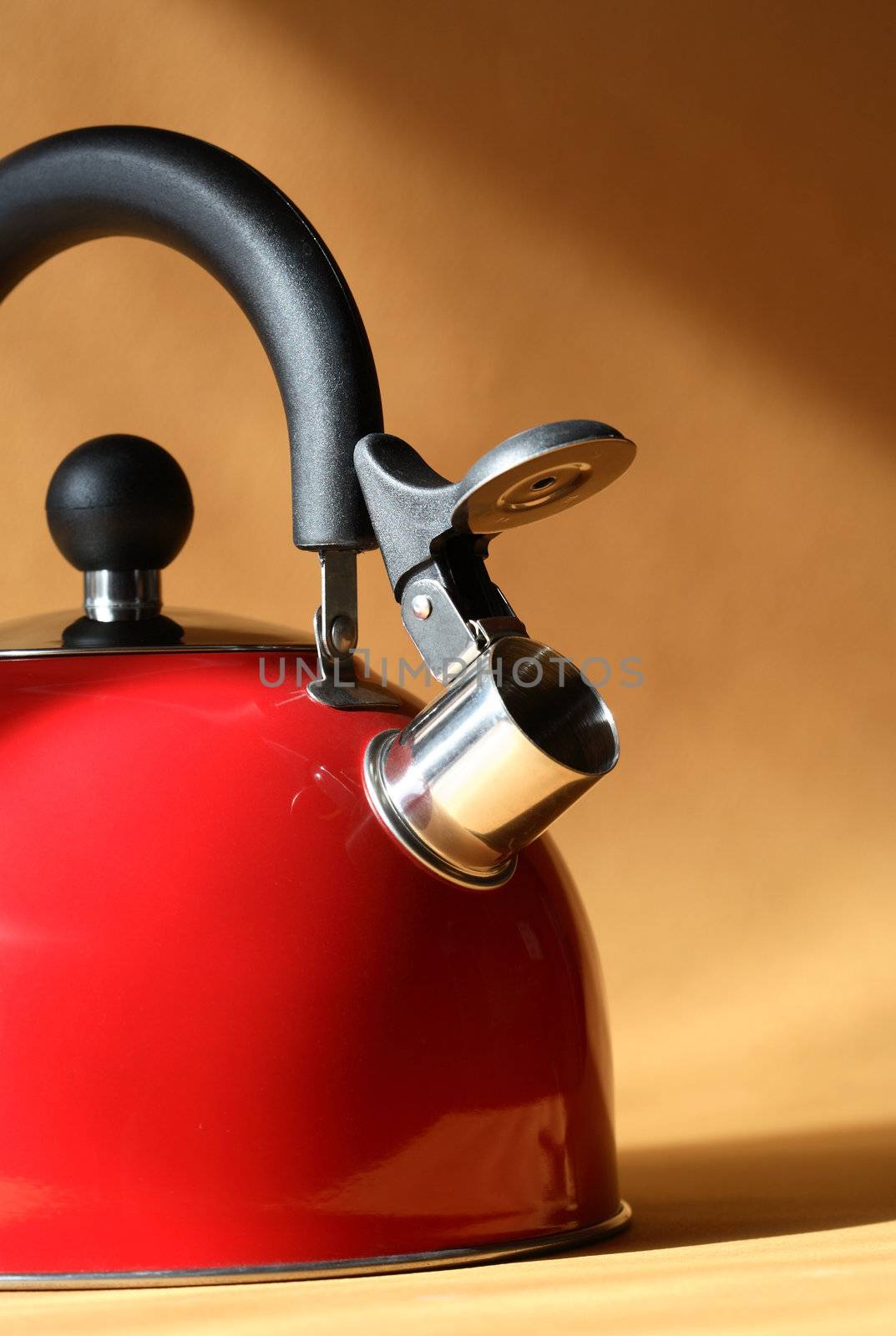 Closeup of red metal kettle on background with sunbeam