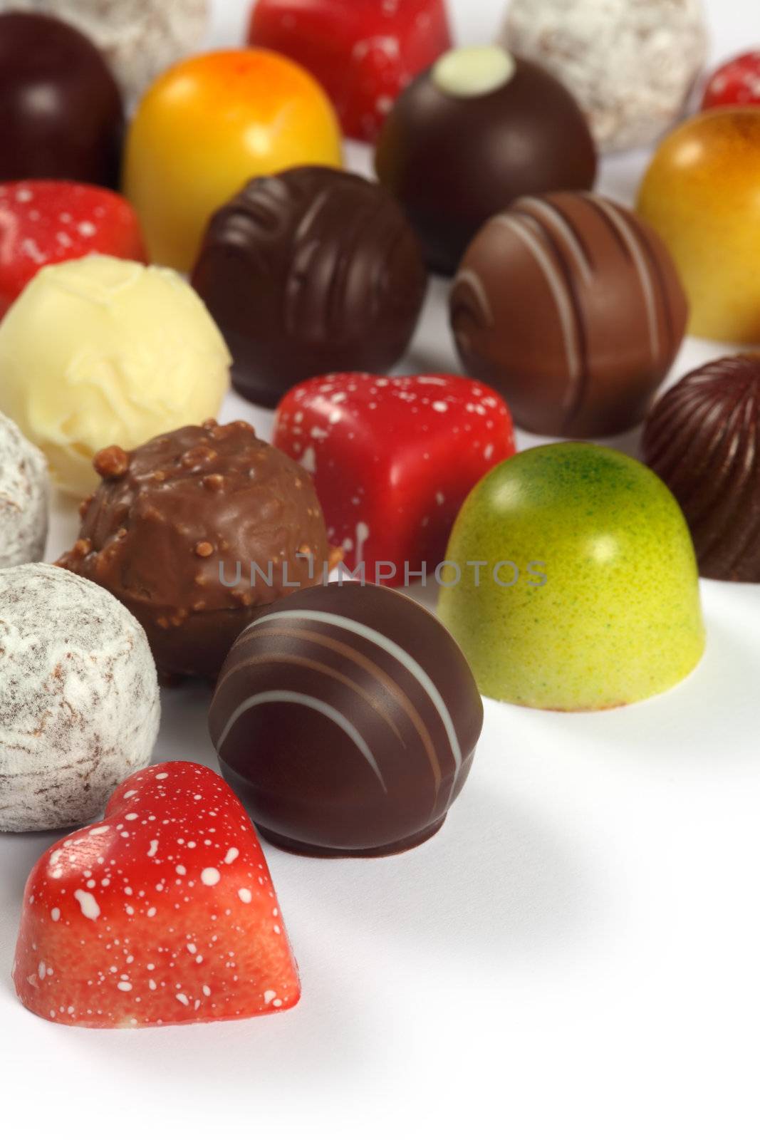 Photo of assorted truffles, pralines, and liqueur filled chocolates on white background.