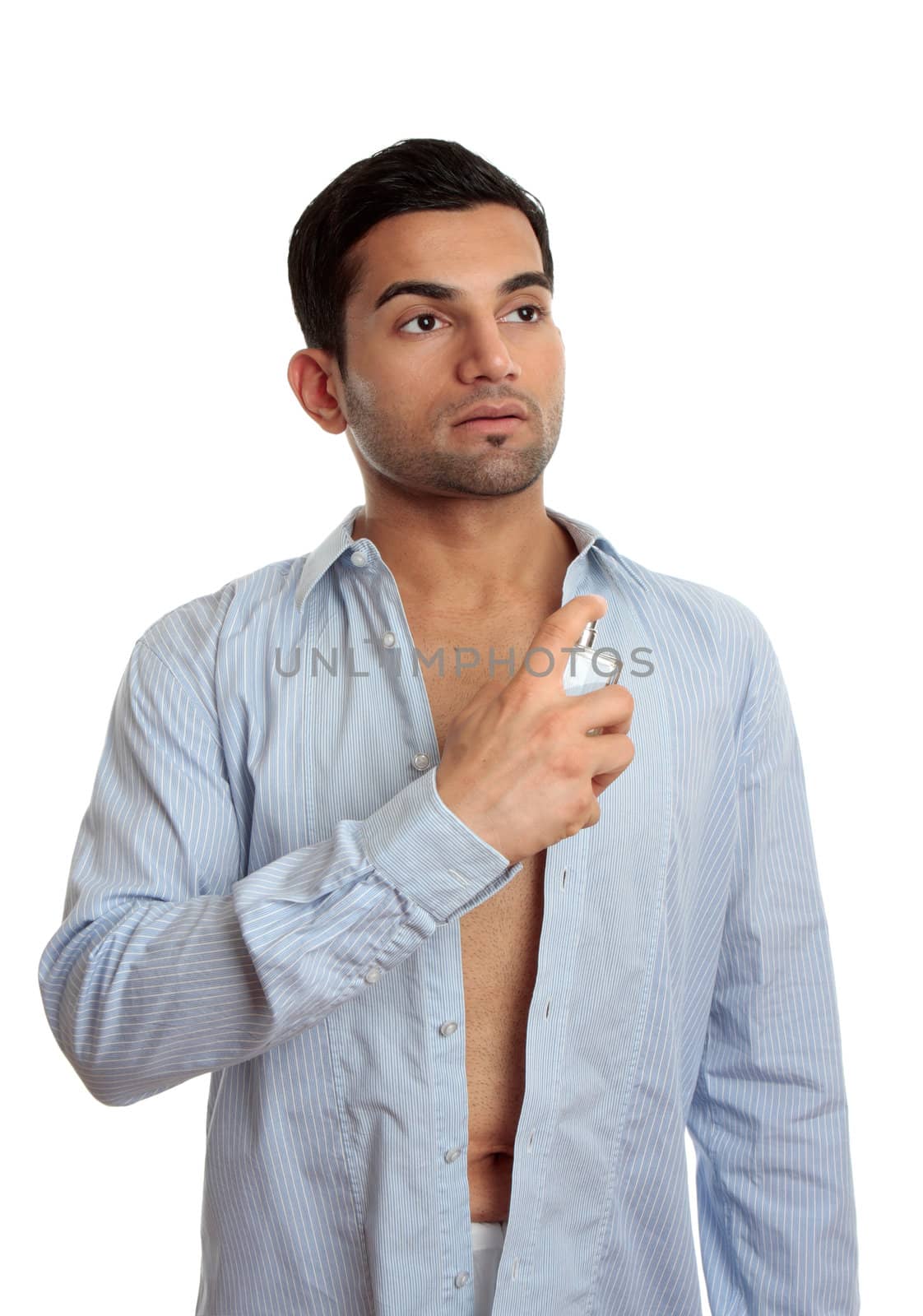 A man in the process of getting ready and dressed, sprays some cologne on skin.