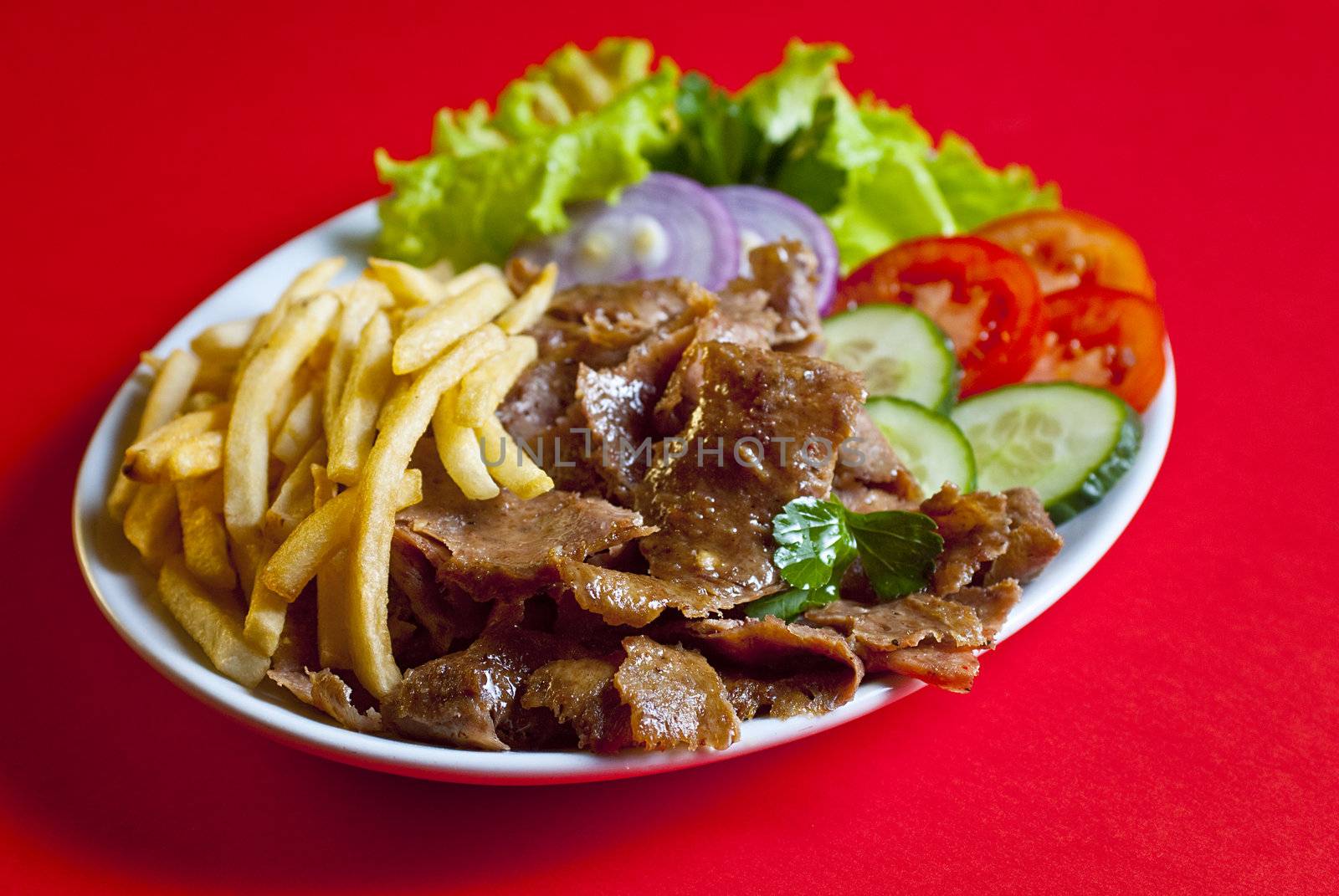 Traditional turkish doner kebab served on white plate with potatoes and vegetable mix