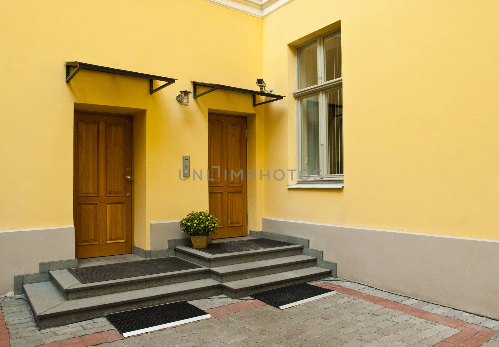 Entrance to yellow home - two brown metal doors and window