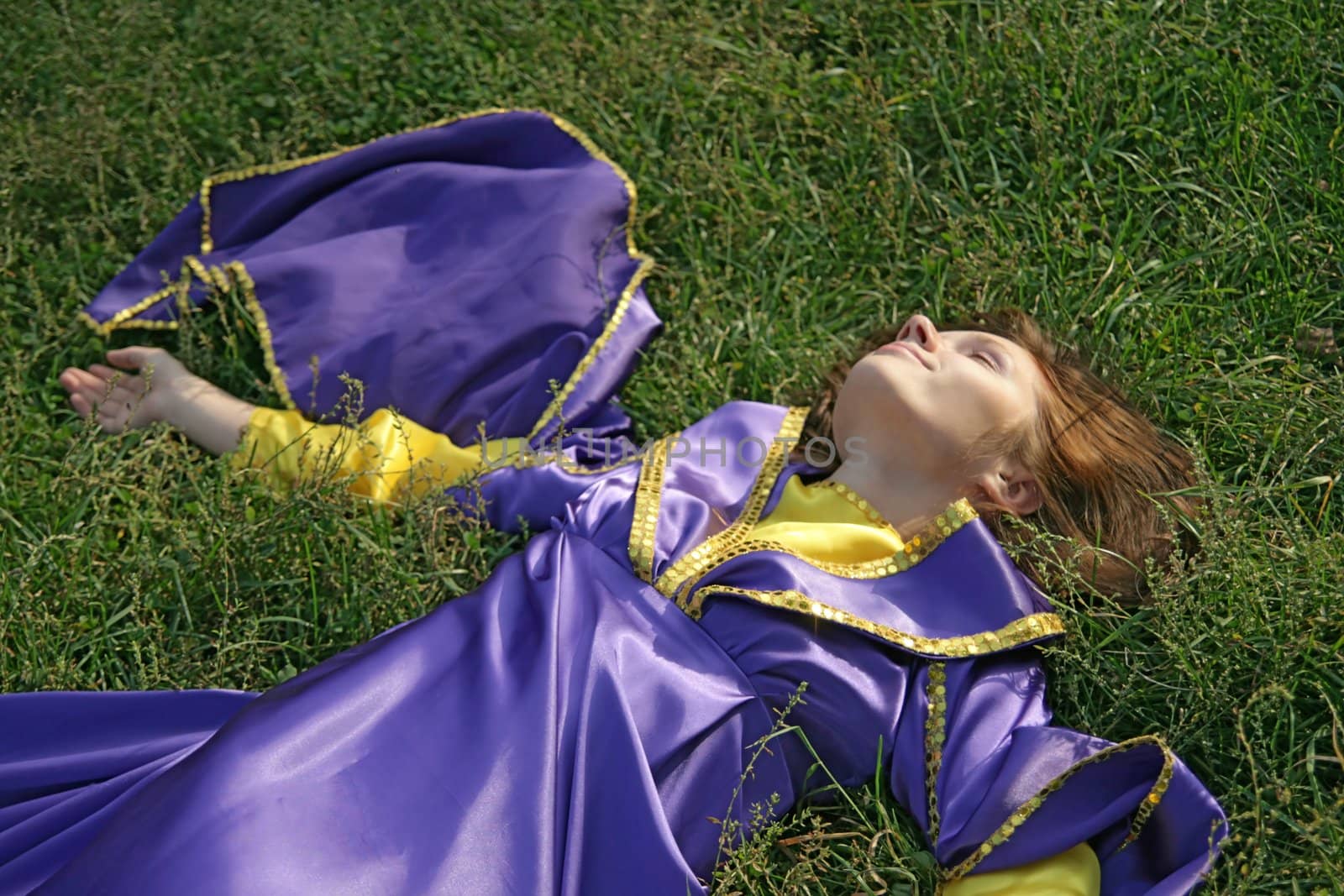 Young womai in a fancy dress laying on grass
