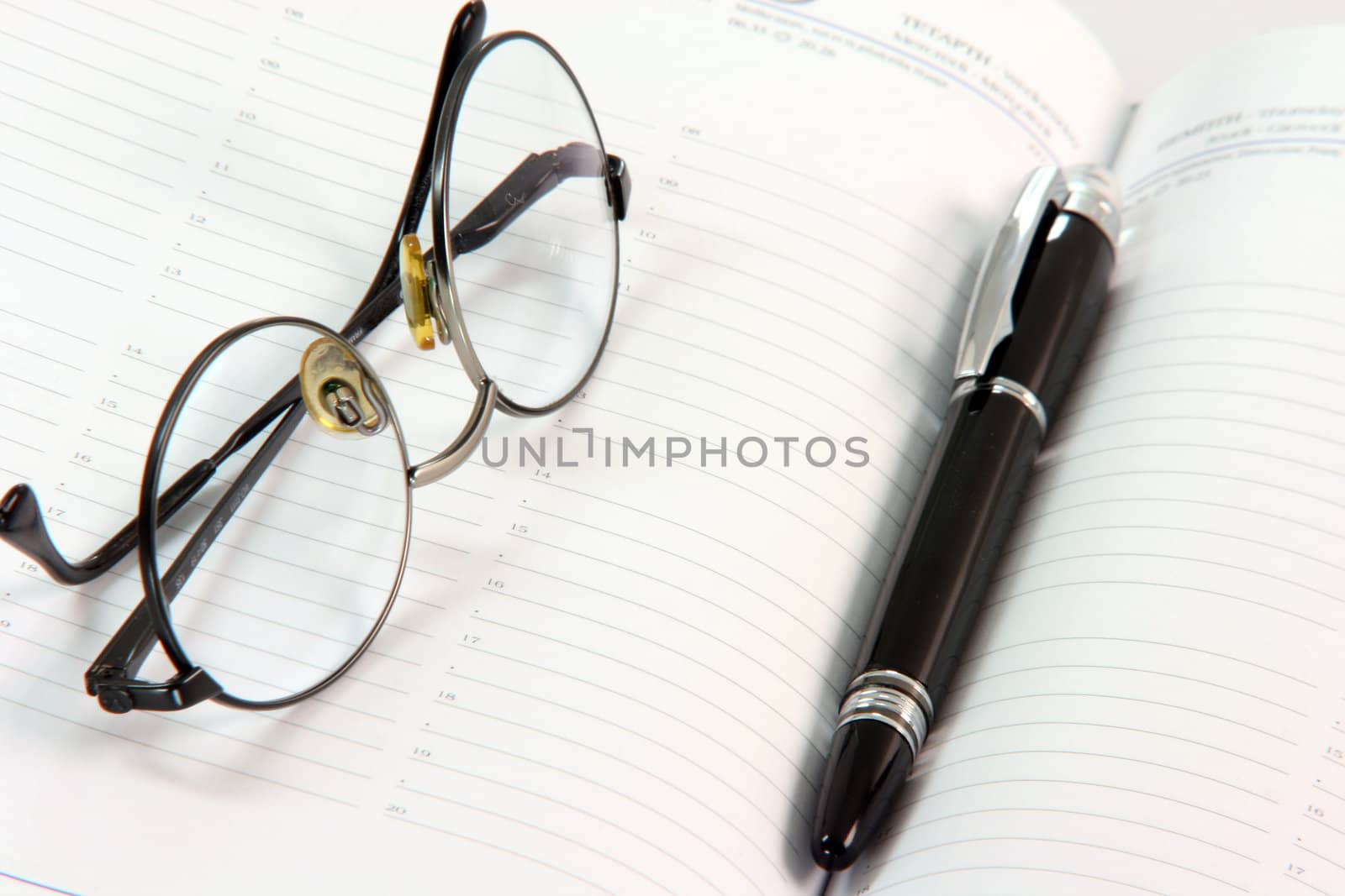 spectacles with black ball pen on open diary business concepts