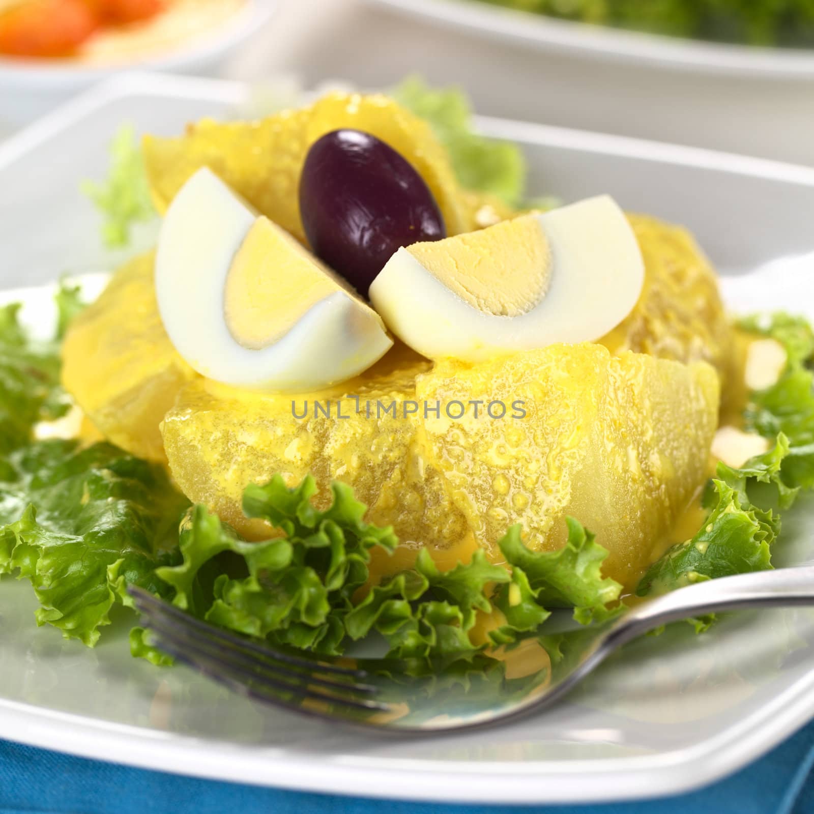 Peruvian appetizer called Papa a la Huancaina made of cooked potatoes, Huancaina sauce, boiled eggs and olives (Selective Focus, Focus on the front of the potatoes and the eggs)