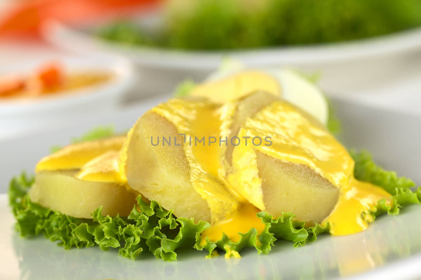 Peruvian appetizer called Papa a la Huancaina made of cooked potatoes, Huancaina sauce and boiled eggs (Selective Focus, Focus on the front of the two potato slices on the right)