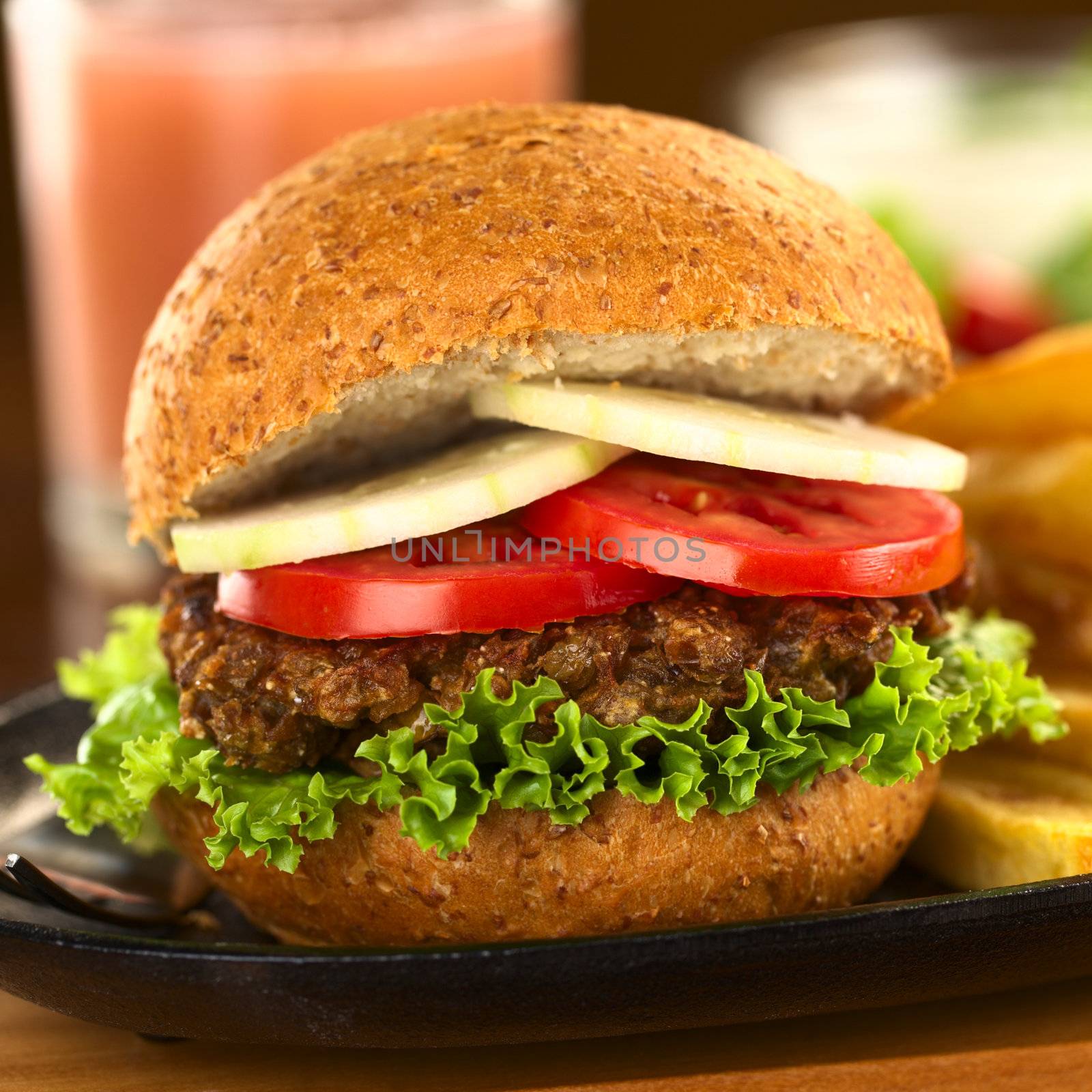 Vegetarian lentil burger in wholewheat bun with lettuce, tomato and cucumber (Selective Focus, Focus on the front of the sandwich) 