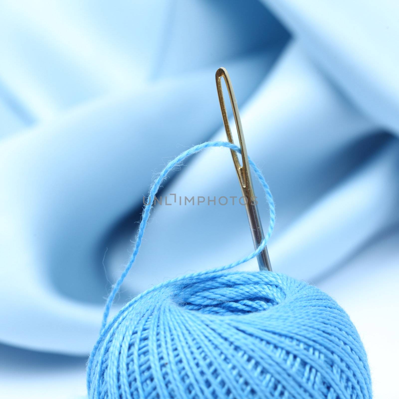 thread on blue silk background close up