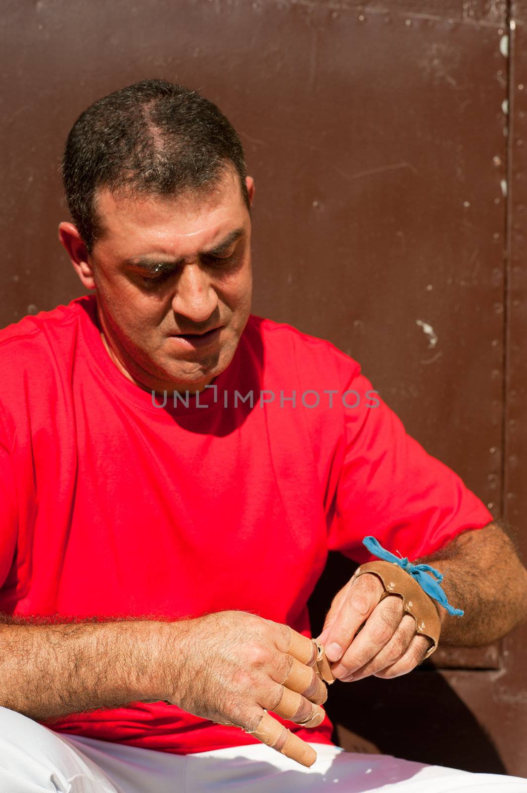 Traditional Spanish pelota player ritually wrapping his fingers in plaster protections