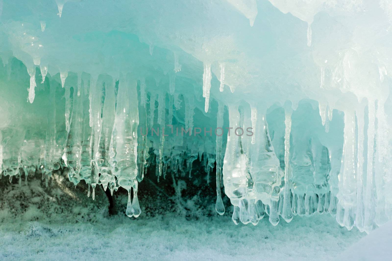 Ice and icicles forming a cave-like structure beautifully illuminated by sunlight.