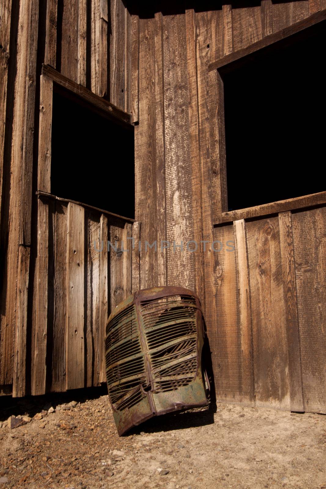 A rusty old truck grill against a barn. by jeremywhat