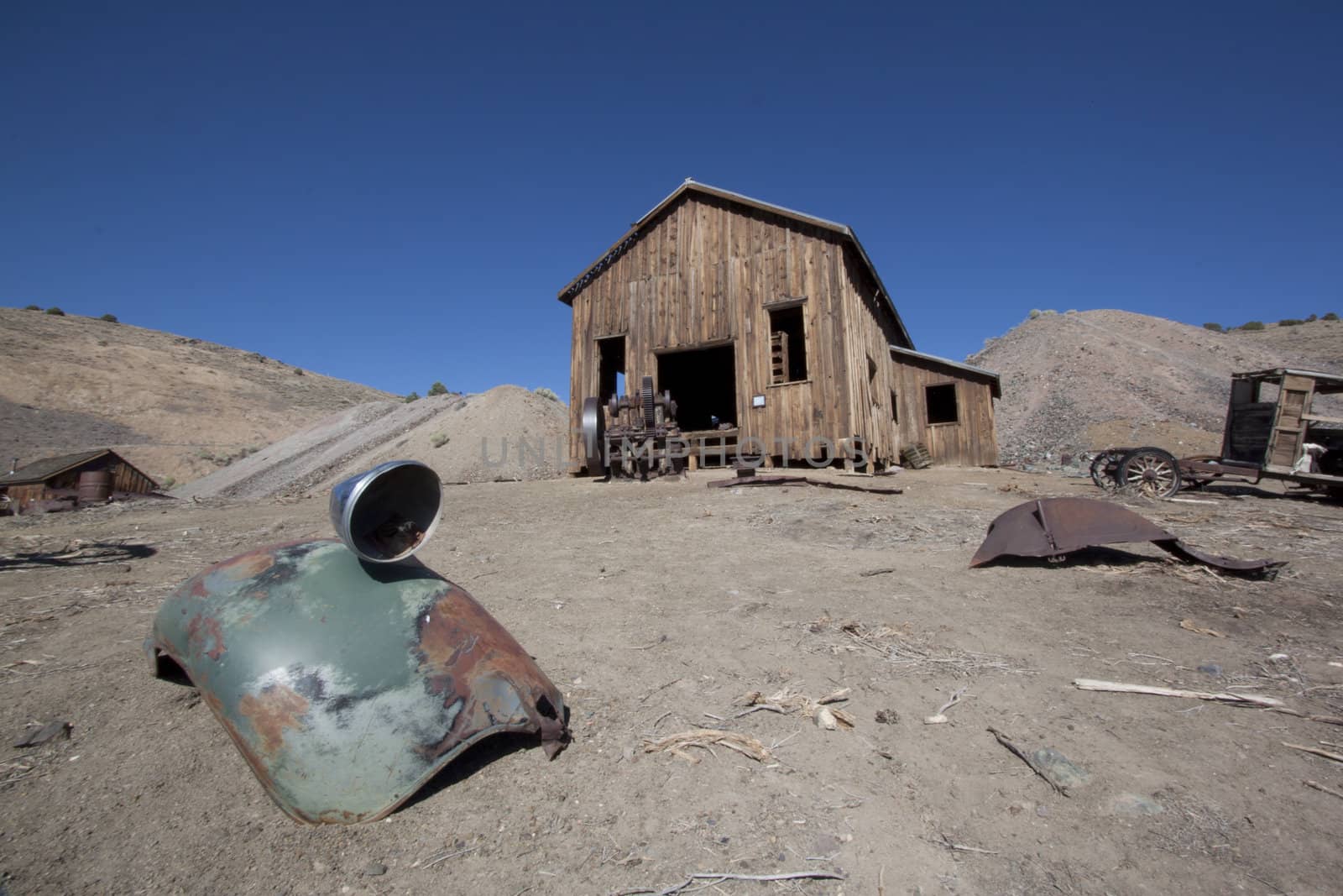 A rusty old truck fender in the forground and barn in the background.