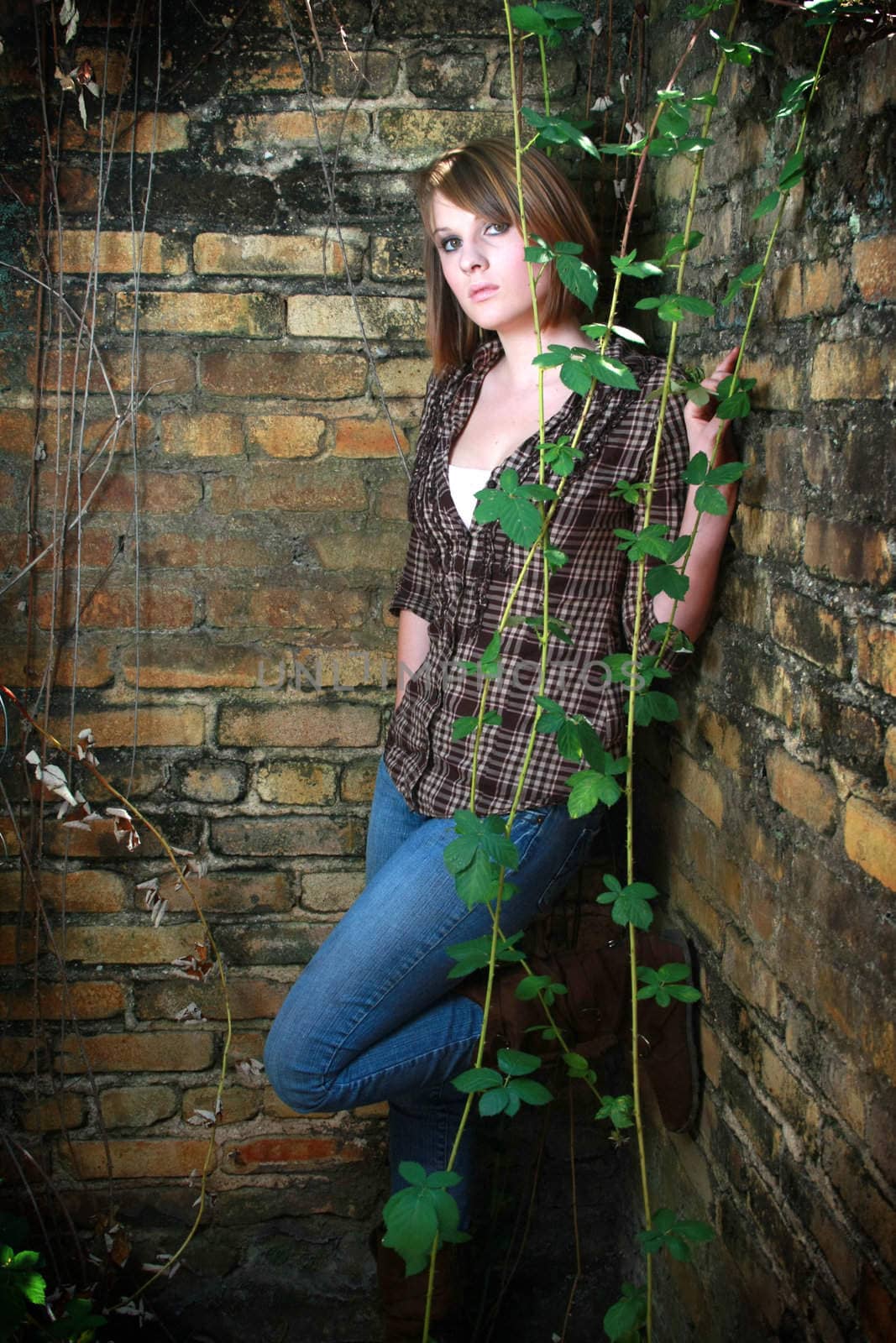 Young woman standing in corner with some vines