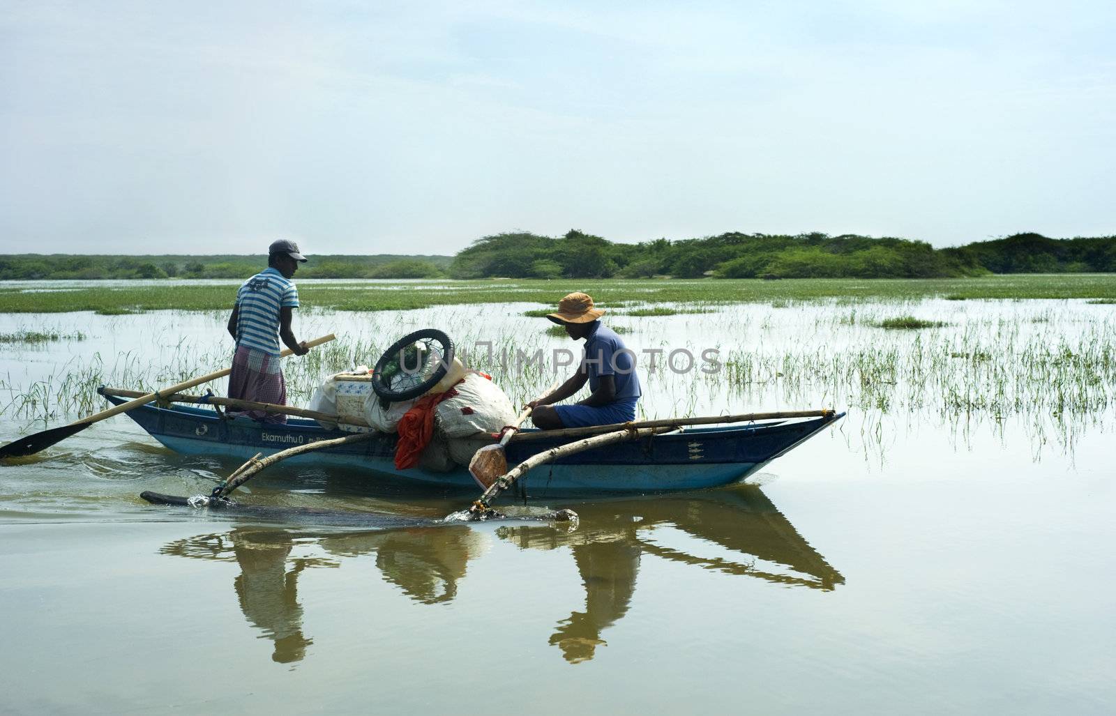 Bentota, Sri Lanka - 13, 2001: Two Sri Lankan men  floating in  the boat  by the small river.