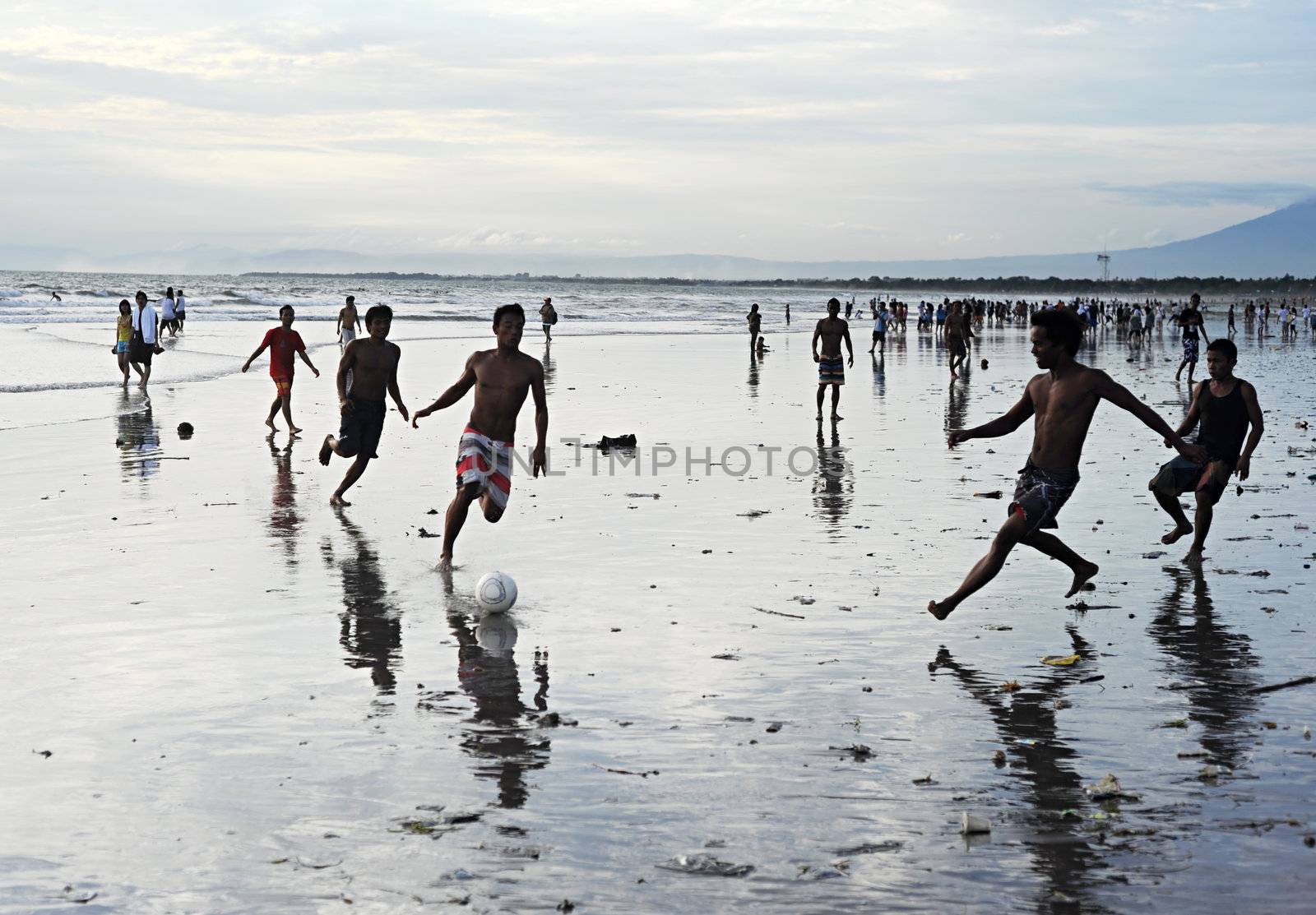 Bali, Indonesia - April 4, 2011: People plaing soccer on the  Kuta beach.Kuta's six-kilometer-long, crescent-shaped surfing beach, protected by a coral reef at its southern end, and long and wide enough for Frisbee contests and soccer games, is famous for its beautiful tropical sunsets