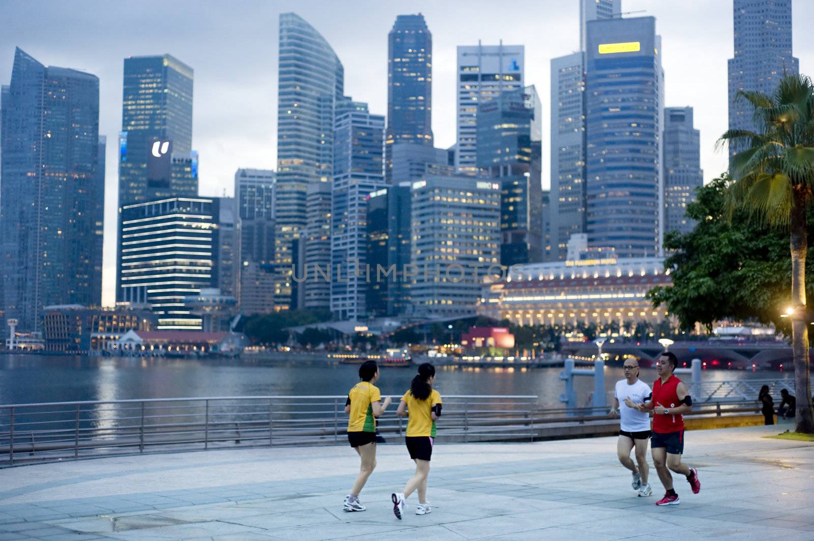 Singapore, Republic of Singapore - May 3, 2011: People running in the evening on embankment in front of business center. Running is very popular sports in Singapore