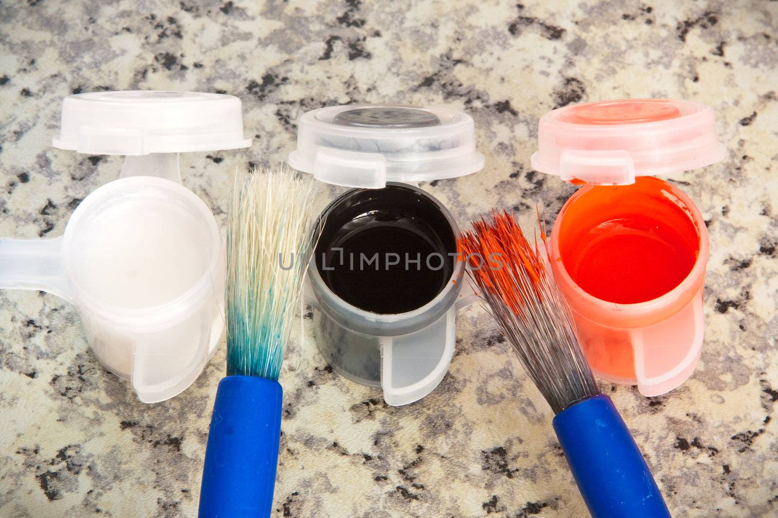 Paint brushes and paint pots on a marble surface