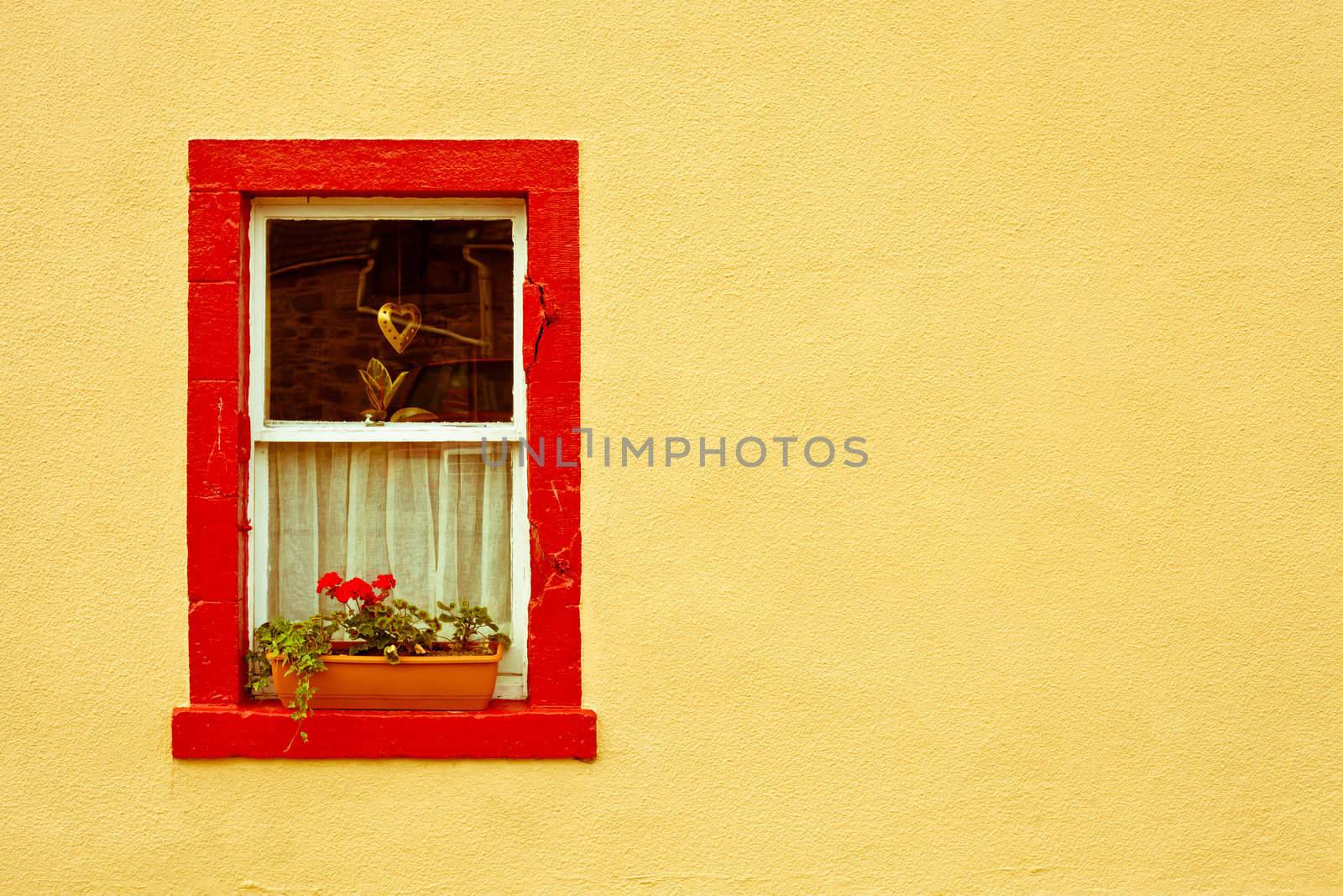 vibrant red window frame in a yellow wall
