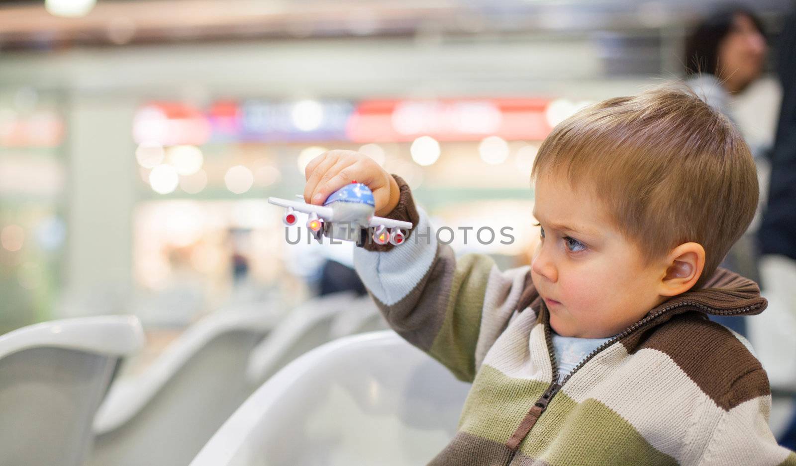 Cute little boy playing with a toy airplane in airport