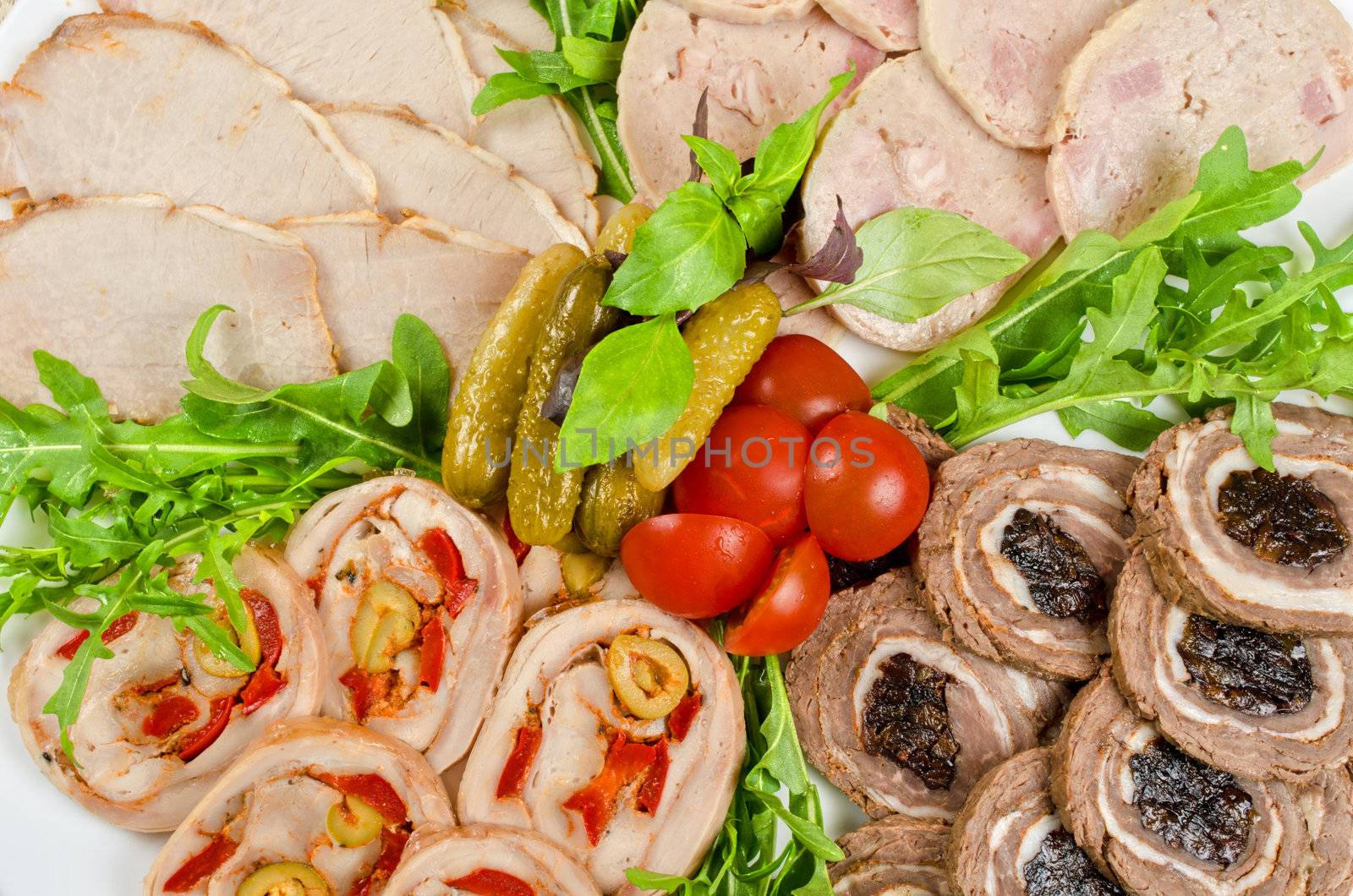 Cutting meat tenderloin stuffed with prune and peper and olive with lettuce, tomatoes, cucumbers and ruccola