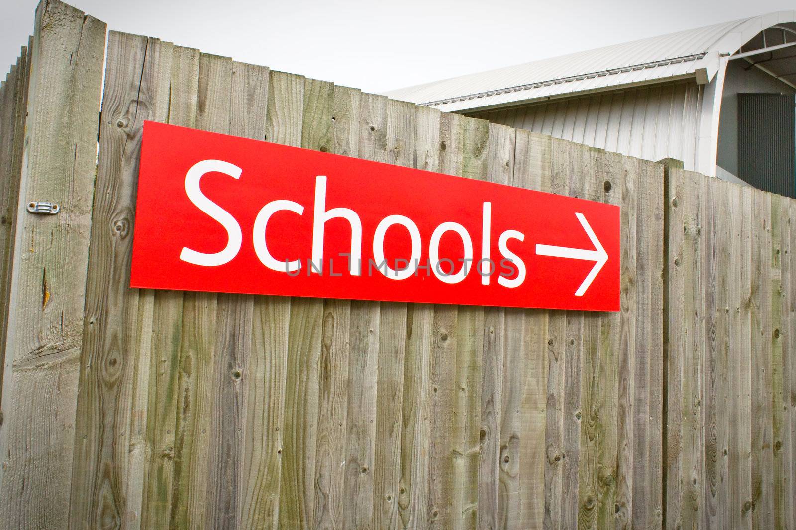 A vibrant red school sign on a wooden fence