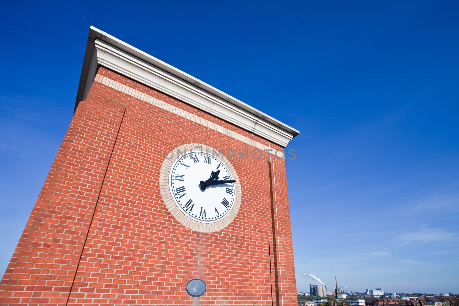 A modern clock tower against a vibrant blue sky
