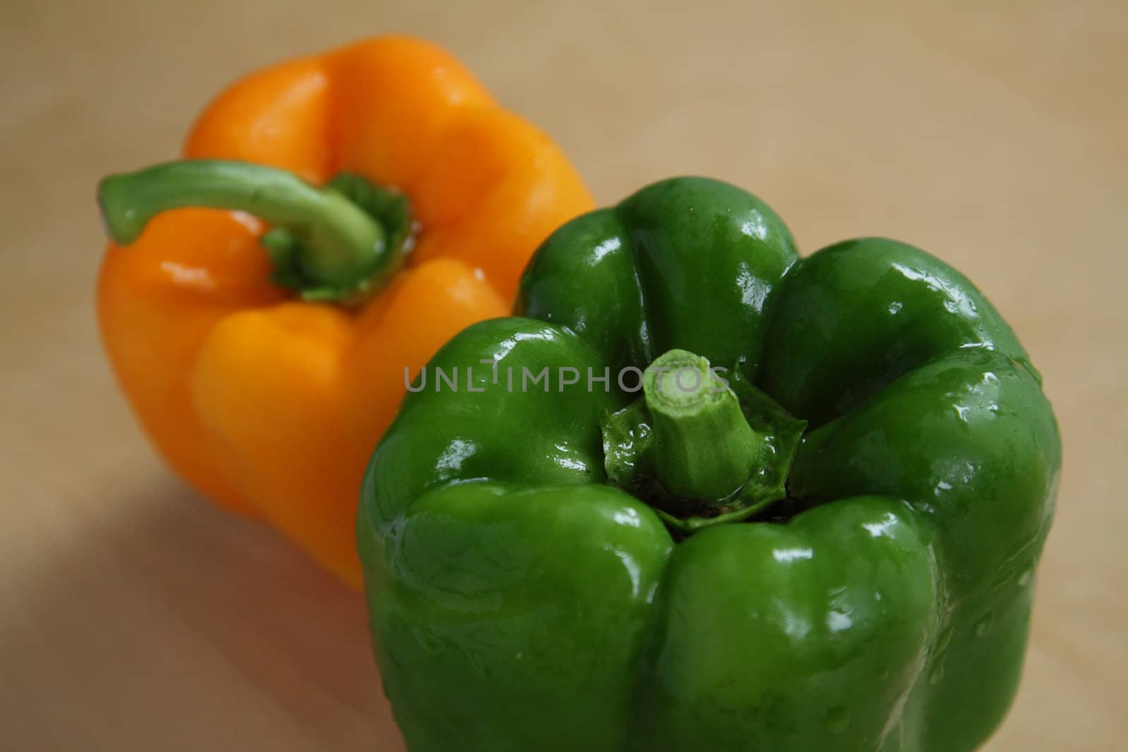 Two peppers, green and orange, on kitchen table