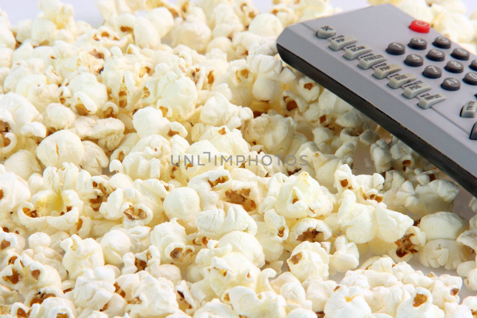 television remote control detail on pop corn background food and entertainment conceps