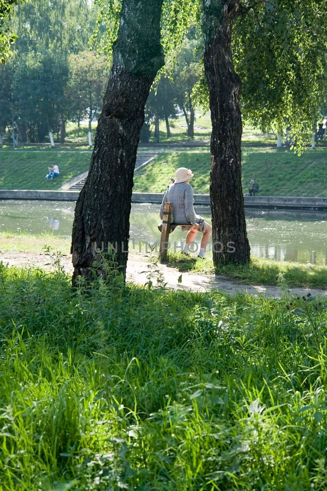 old woman has a rest in park near the river