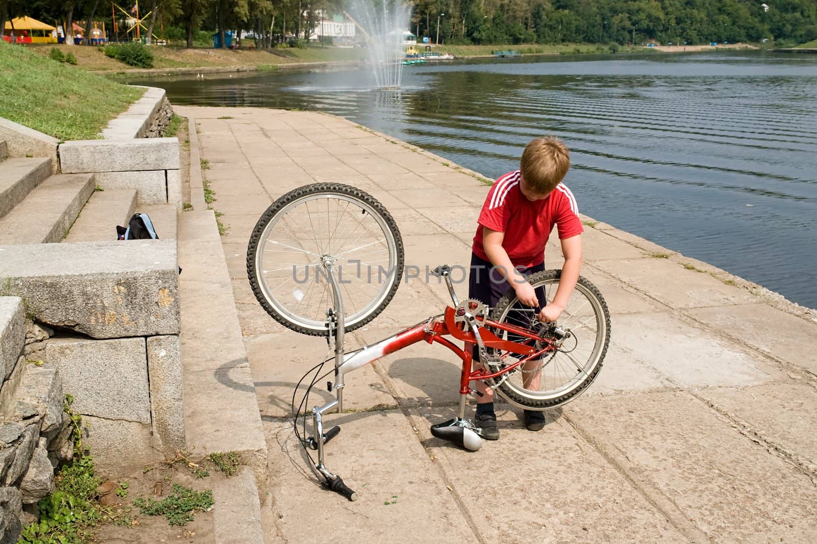little boy repairs the bicycle on quay