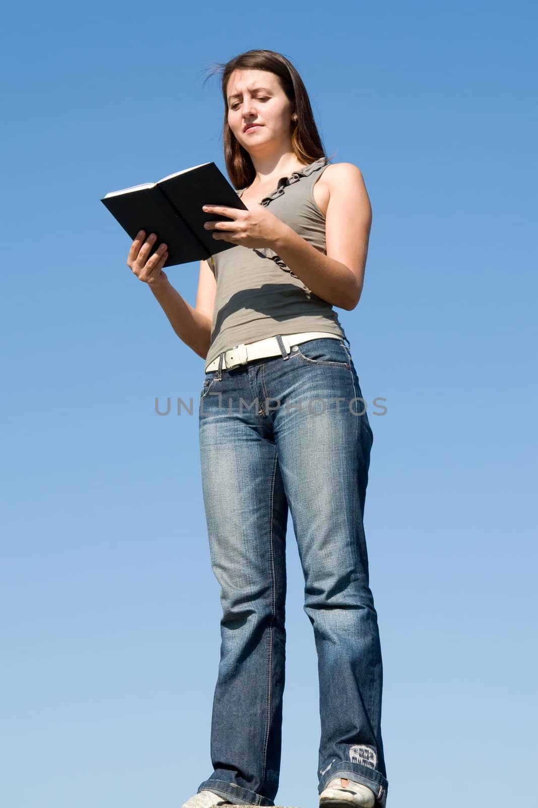 girl reads book with sky at background