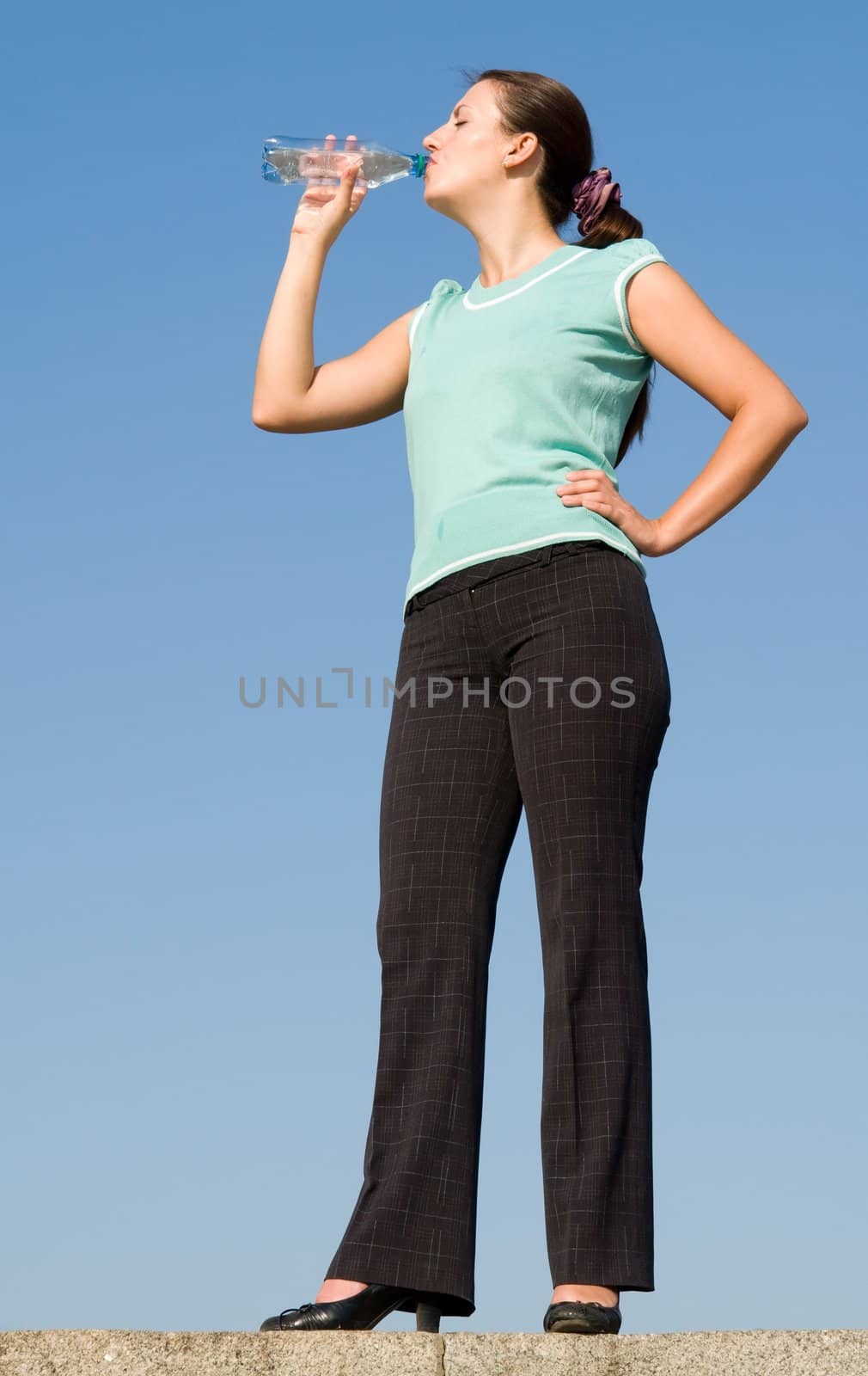 beautiful woman drinks water on a blue sky