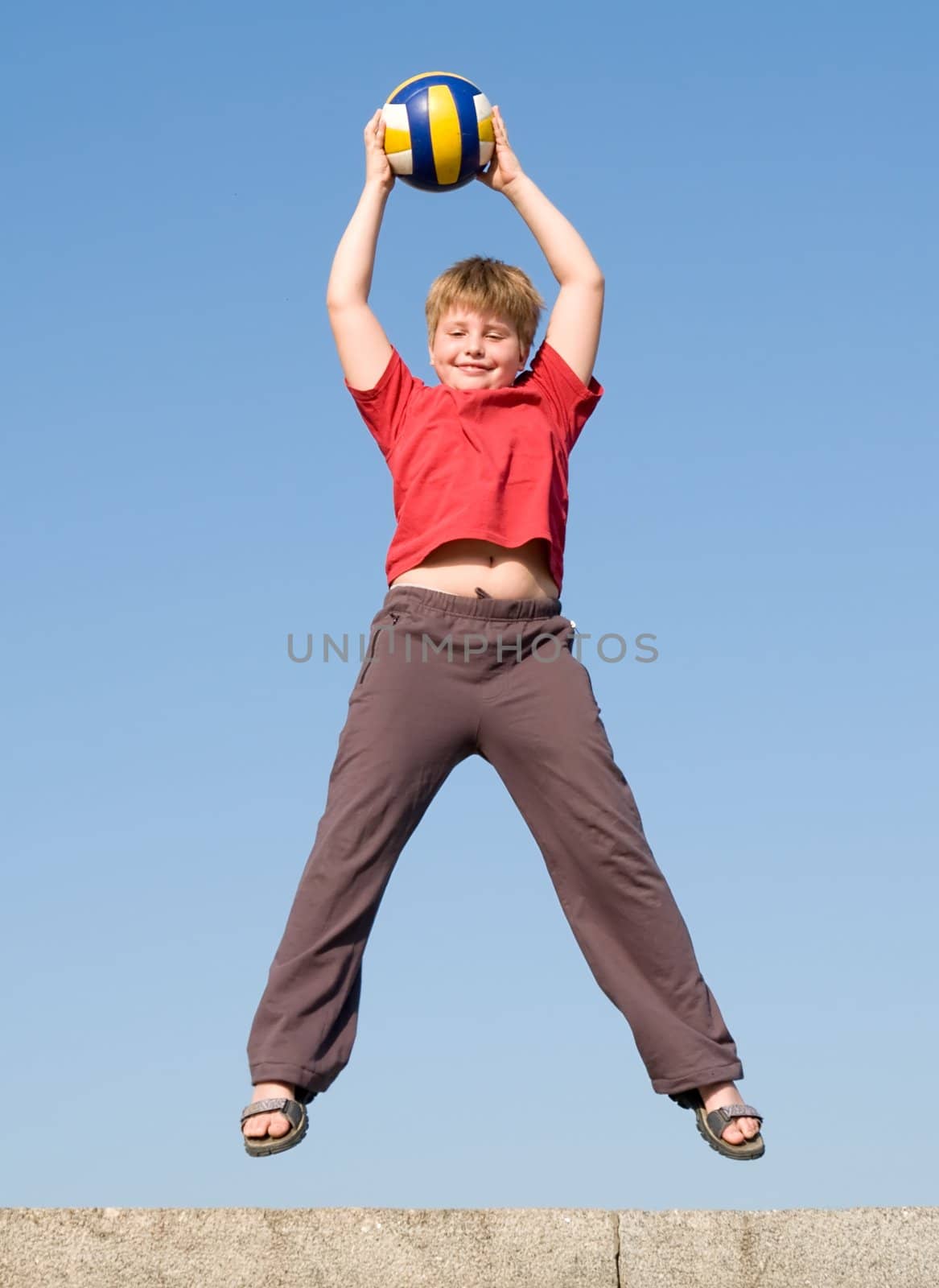 jumping boy with ball on a blue sky