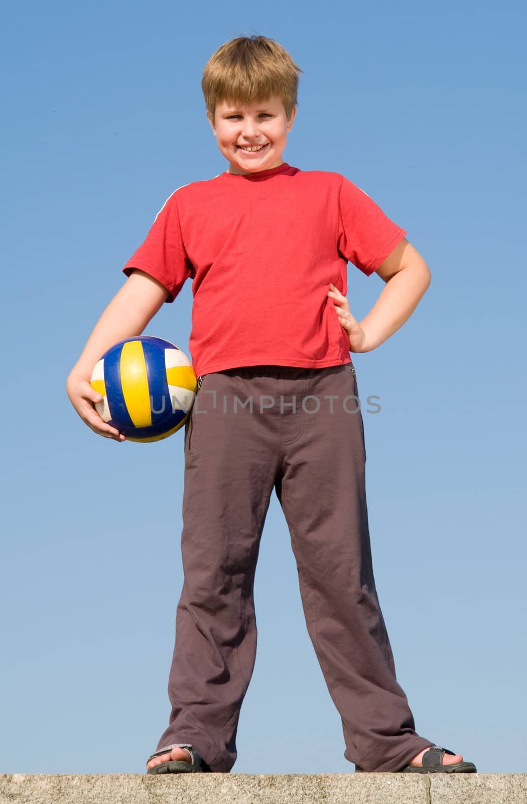 little boy with volleyball ball on a blue sky