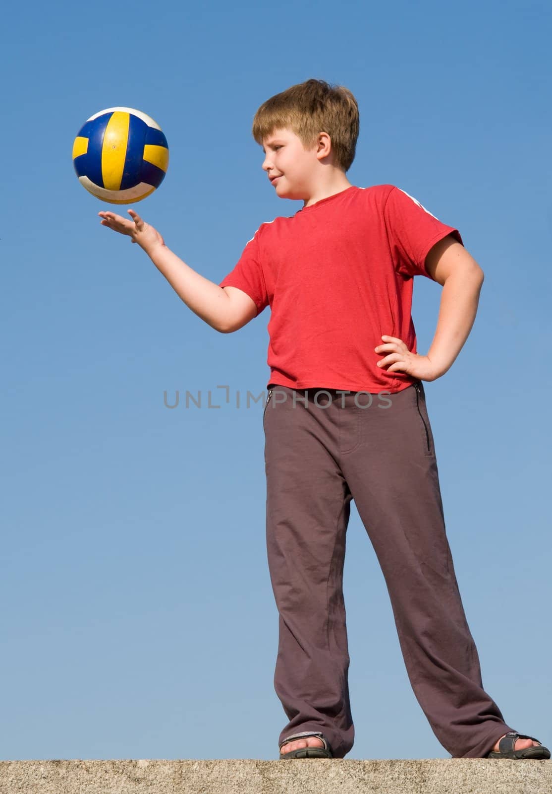 boy throws volleyball ball on a blue sky