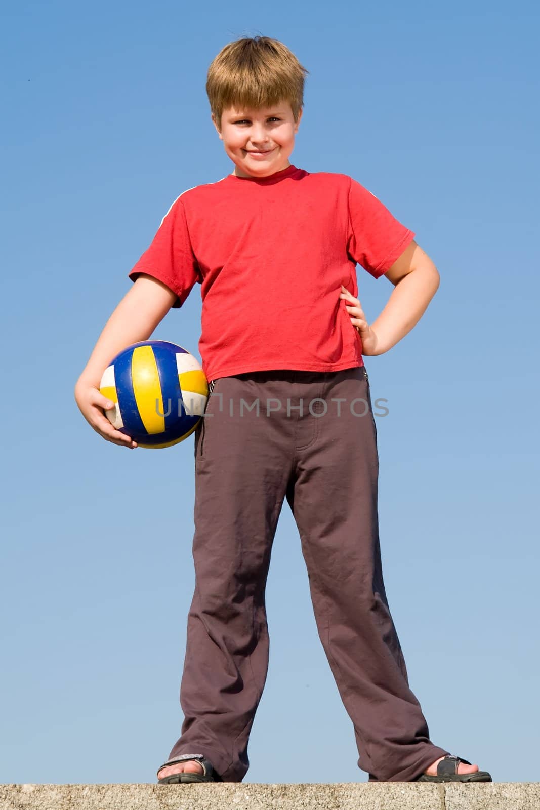 little boy with volleyball ball on a blue sky
