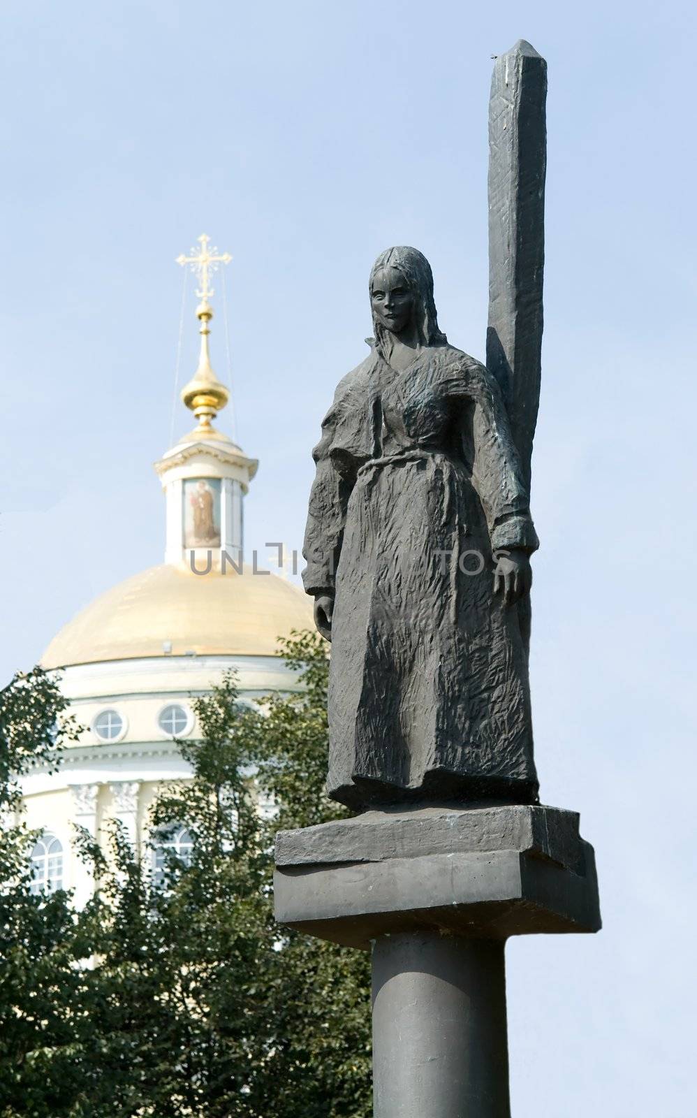 Statue. woman near a column with church at background
