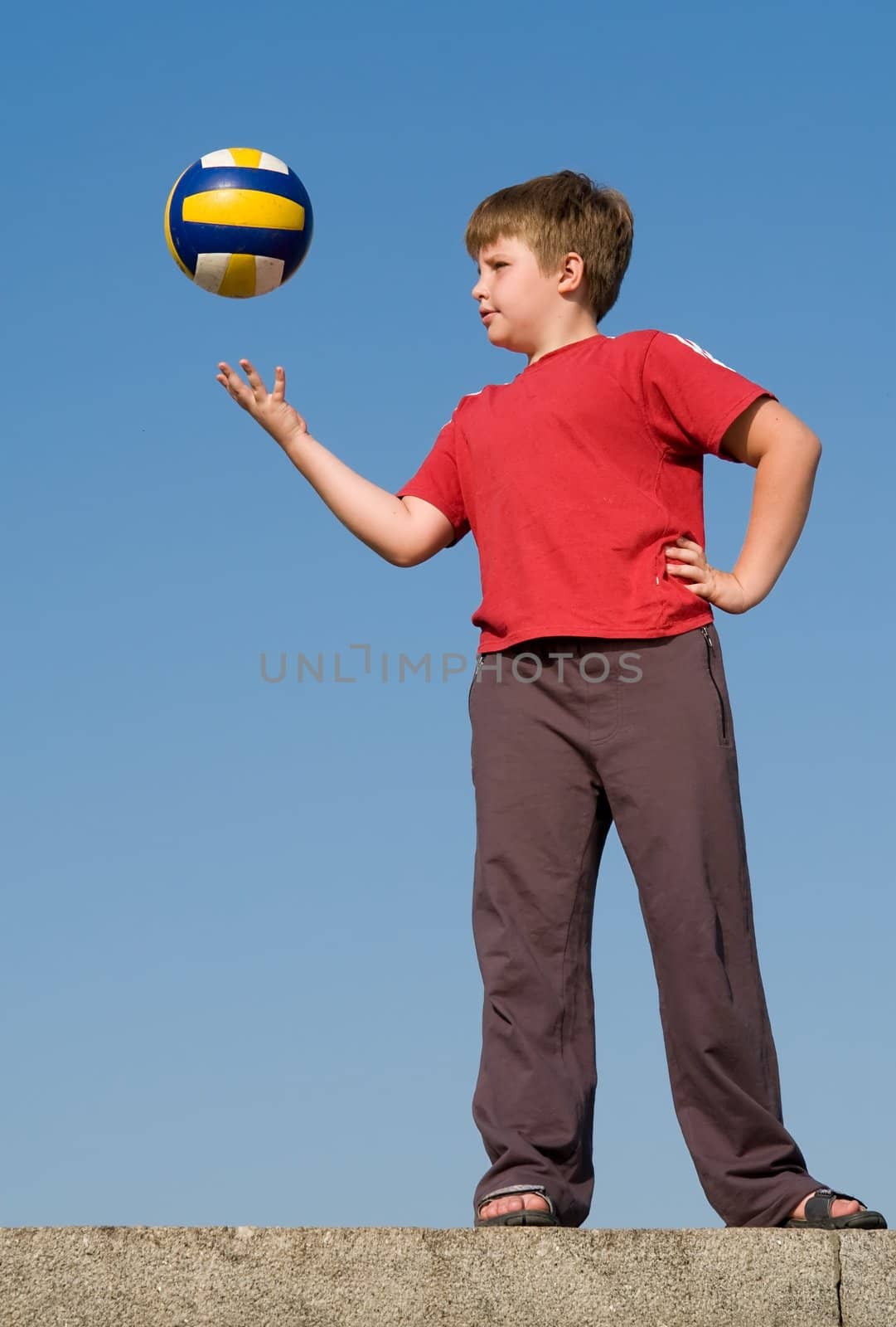 boy throws volleyball ball on a blue sky