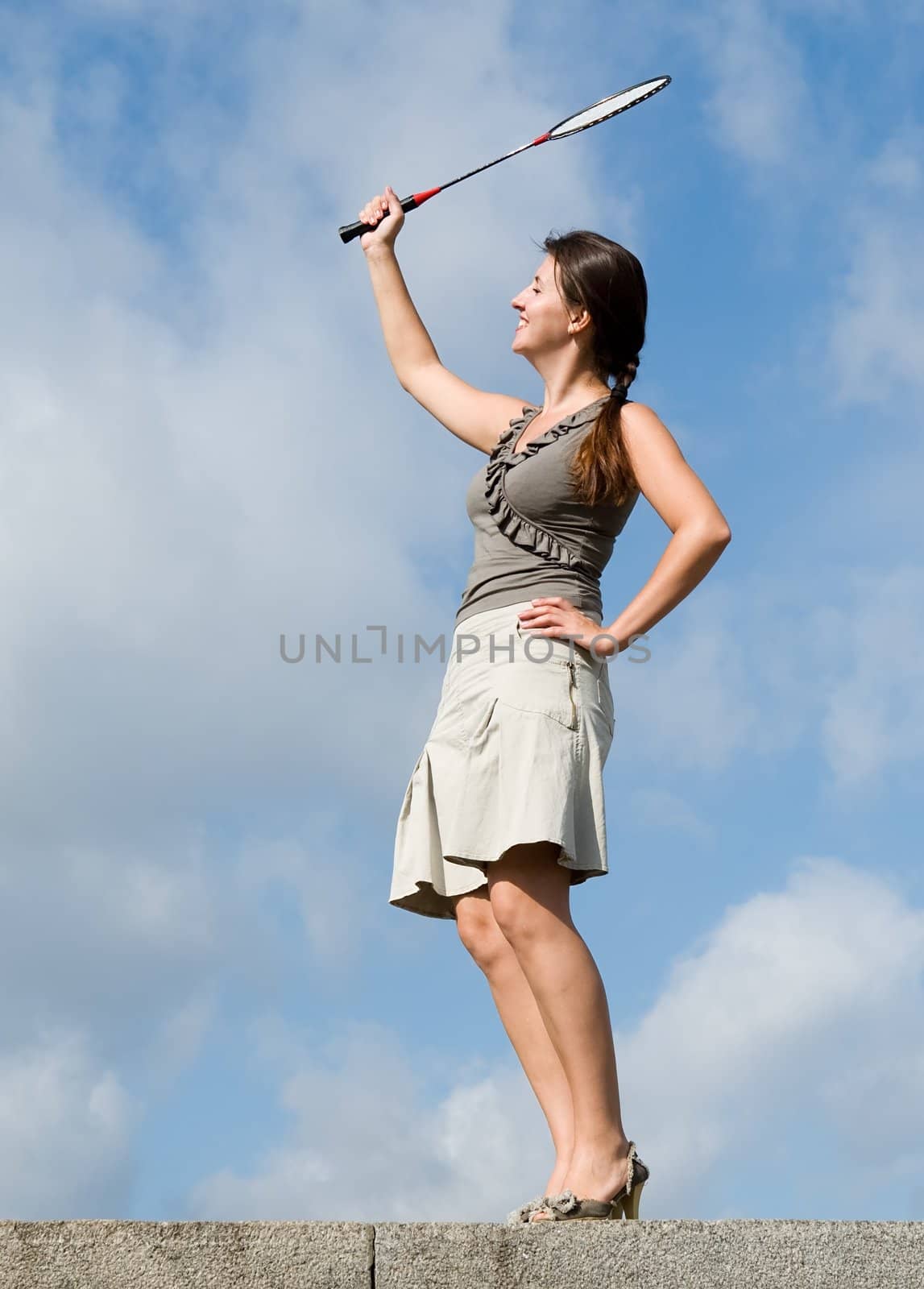 young woman playing badminton on a blue sky