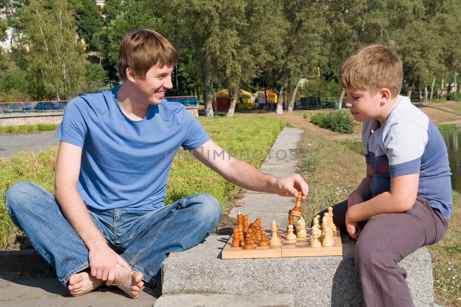 Father playing chess with his boy in park