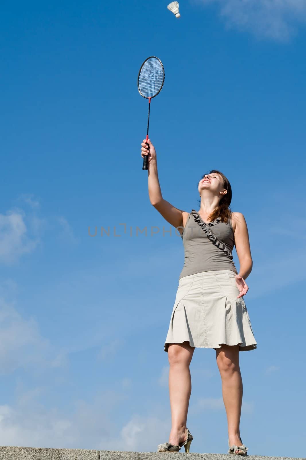 young woman playing badminton on a blue sky